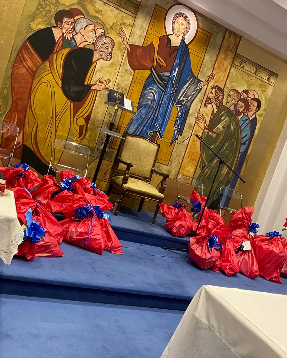 Bolsas de Cáritas preparadas ante el mural del templo