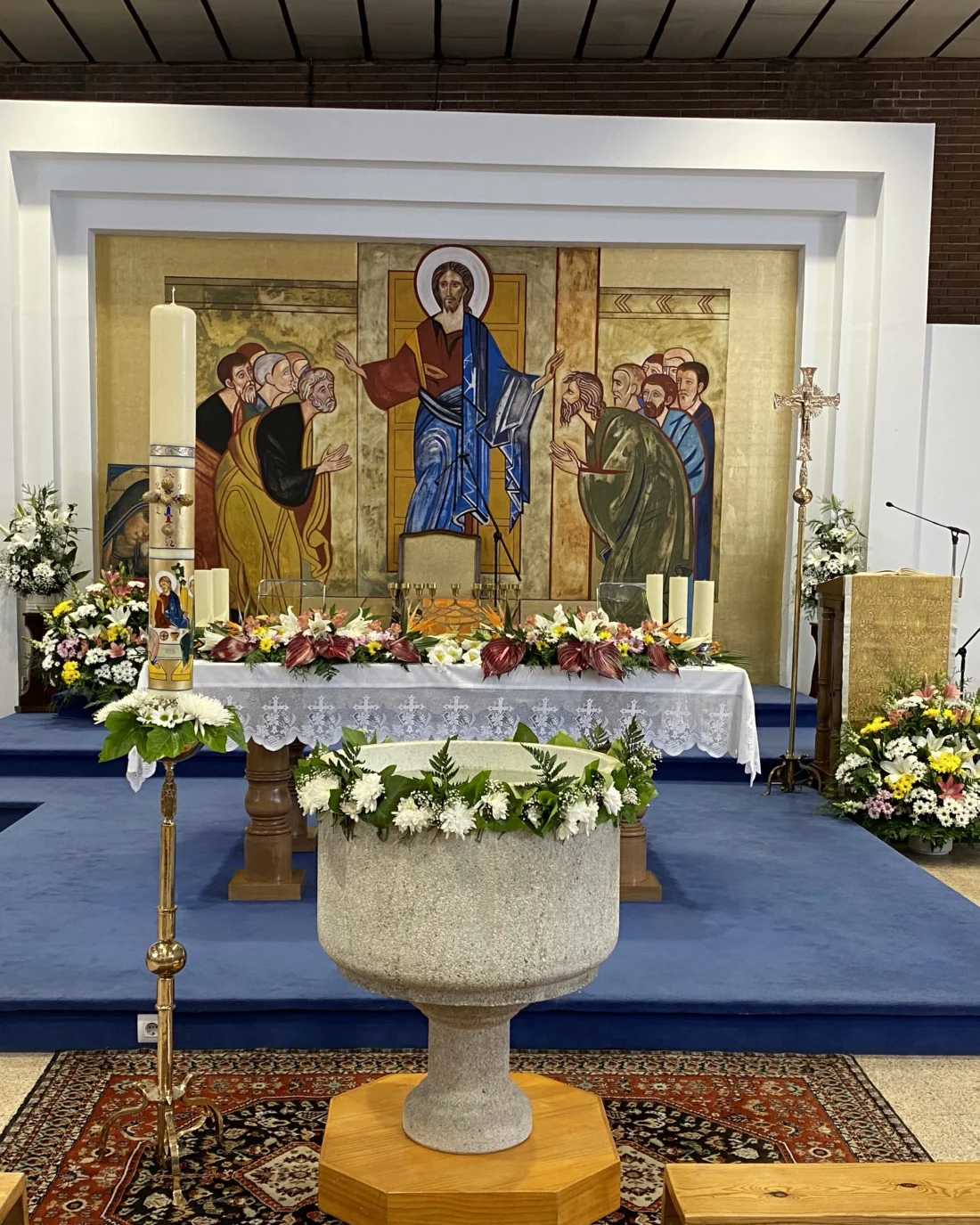Presbiterio de la parroquia con el mural de la Transfiguración y la pila bautismal